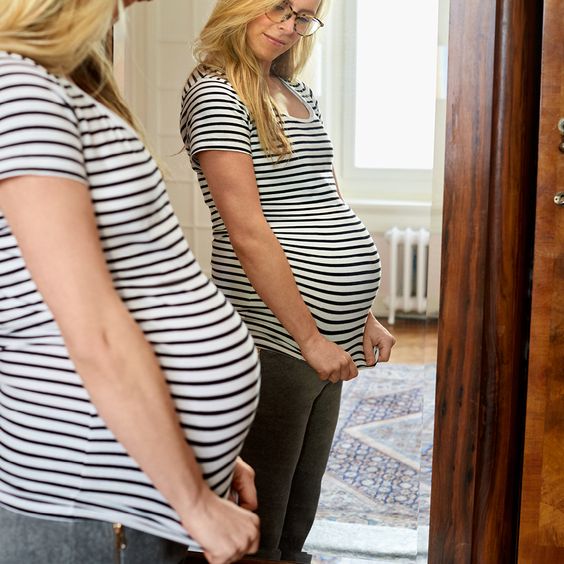 Zwangere vrouw in streepjes t-shirt voor de spiegel. | Zeeman